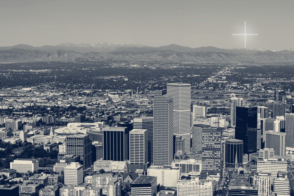 Aerial view of downtown Denver office towers with the Front Range beyond